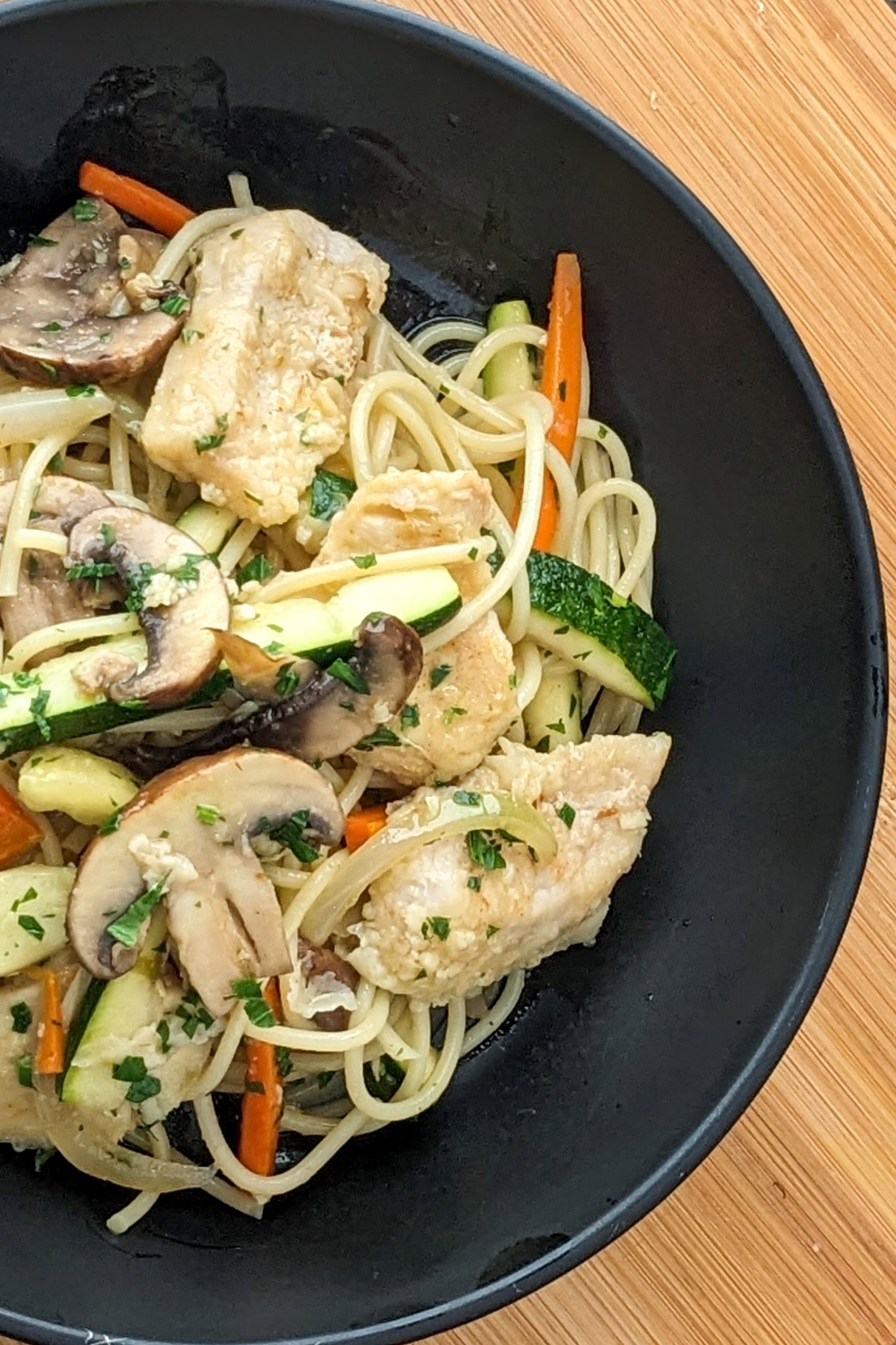 Vibrant lemon pepper chicken pasta with colorful vegetables in a rustic bowl.